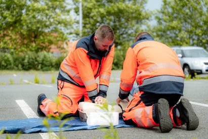 Dva záchranáři při nácviku resuscitace na figuríně venku